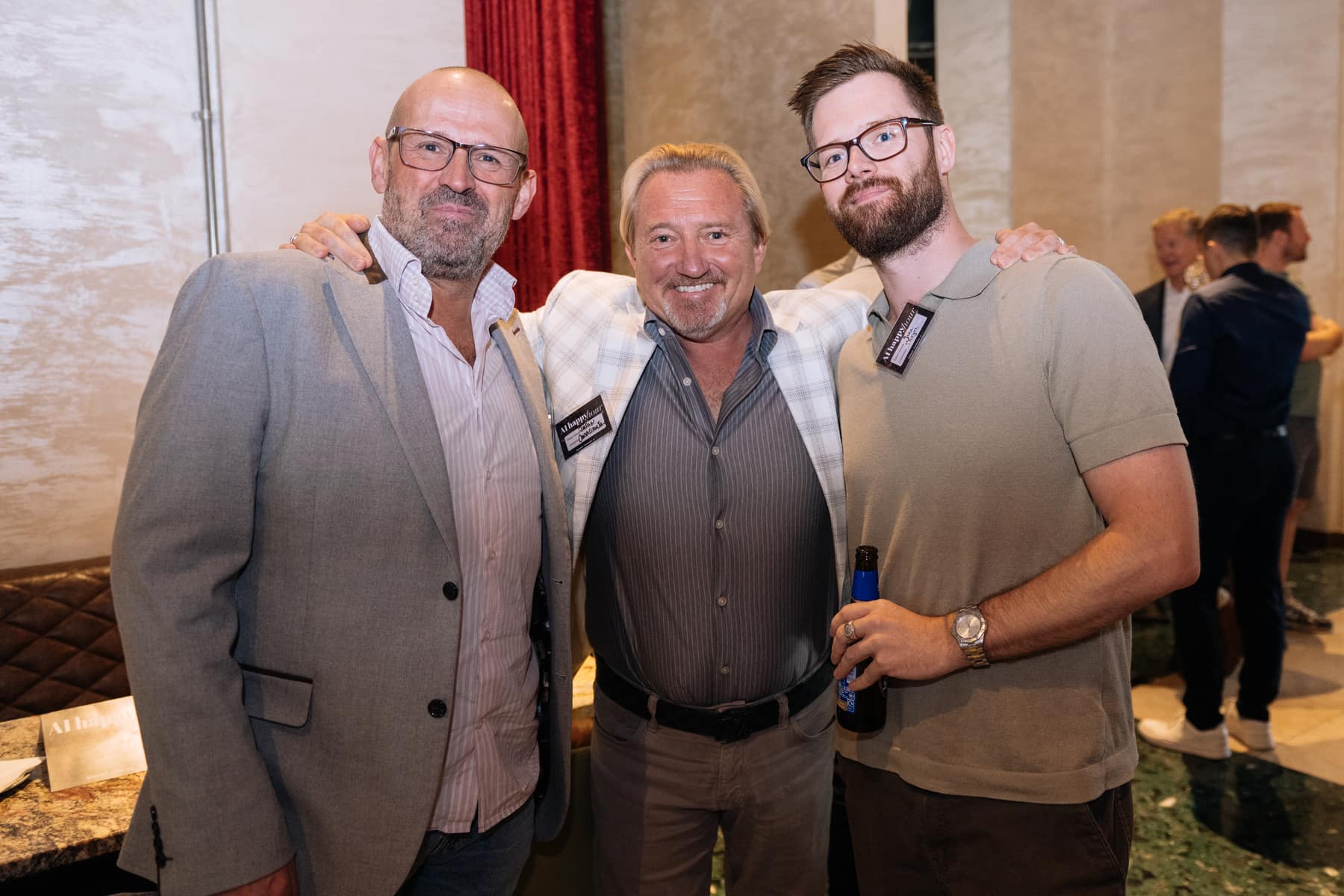 Three guests laughing, drinks in hand, at the London AI Happy Hour in July 2026