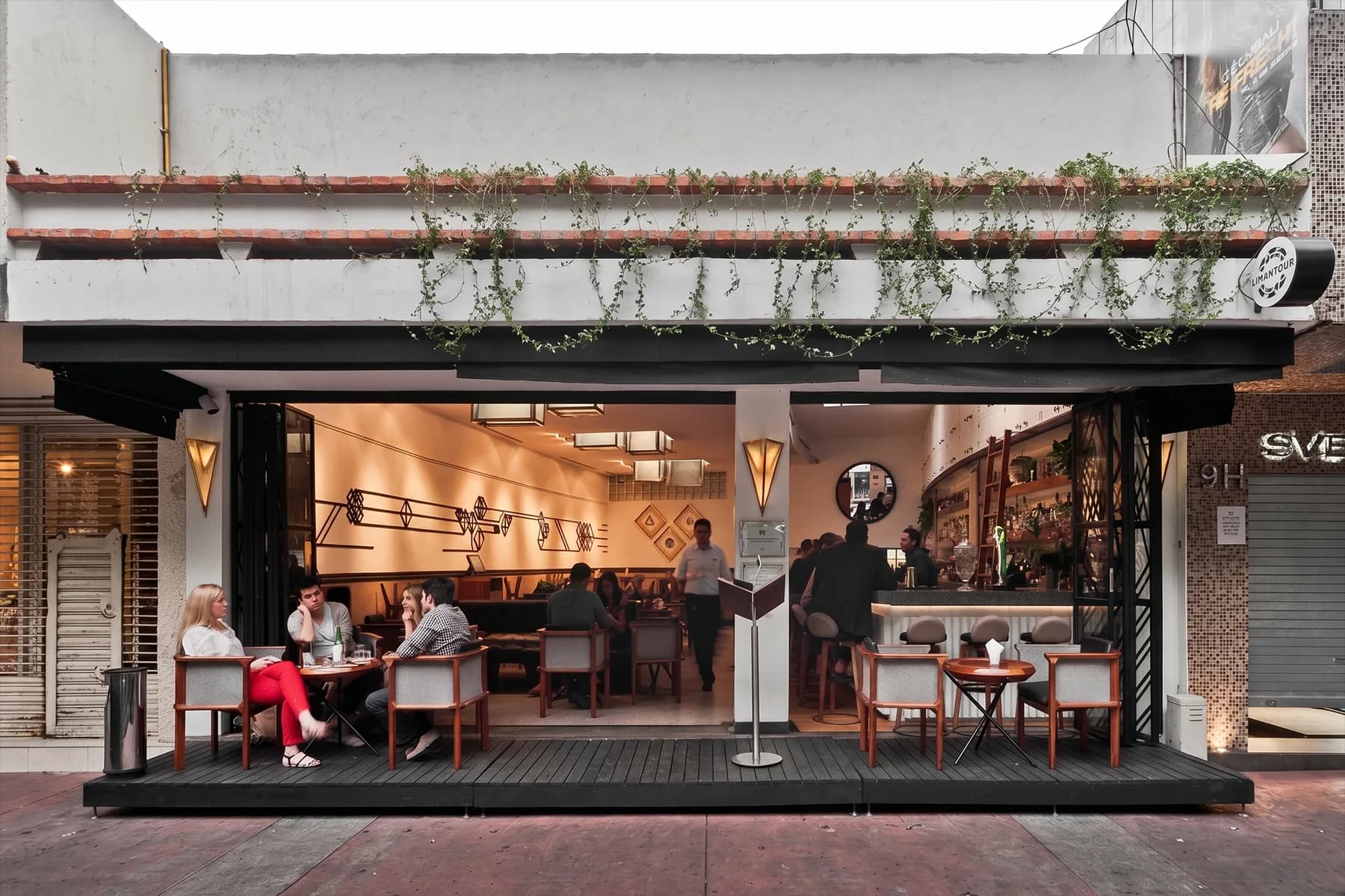 La fachada abierta de Licorería Limantour Polanco al atardecer, con mesas en la terraza bajo una fachada cubierta de hiedra