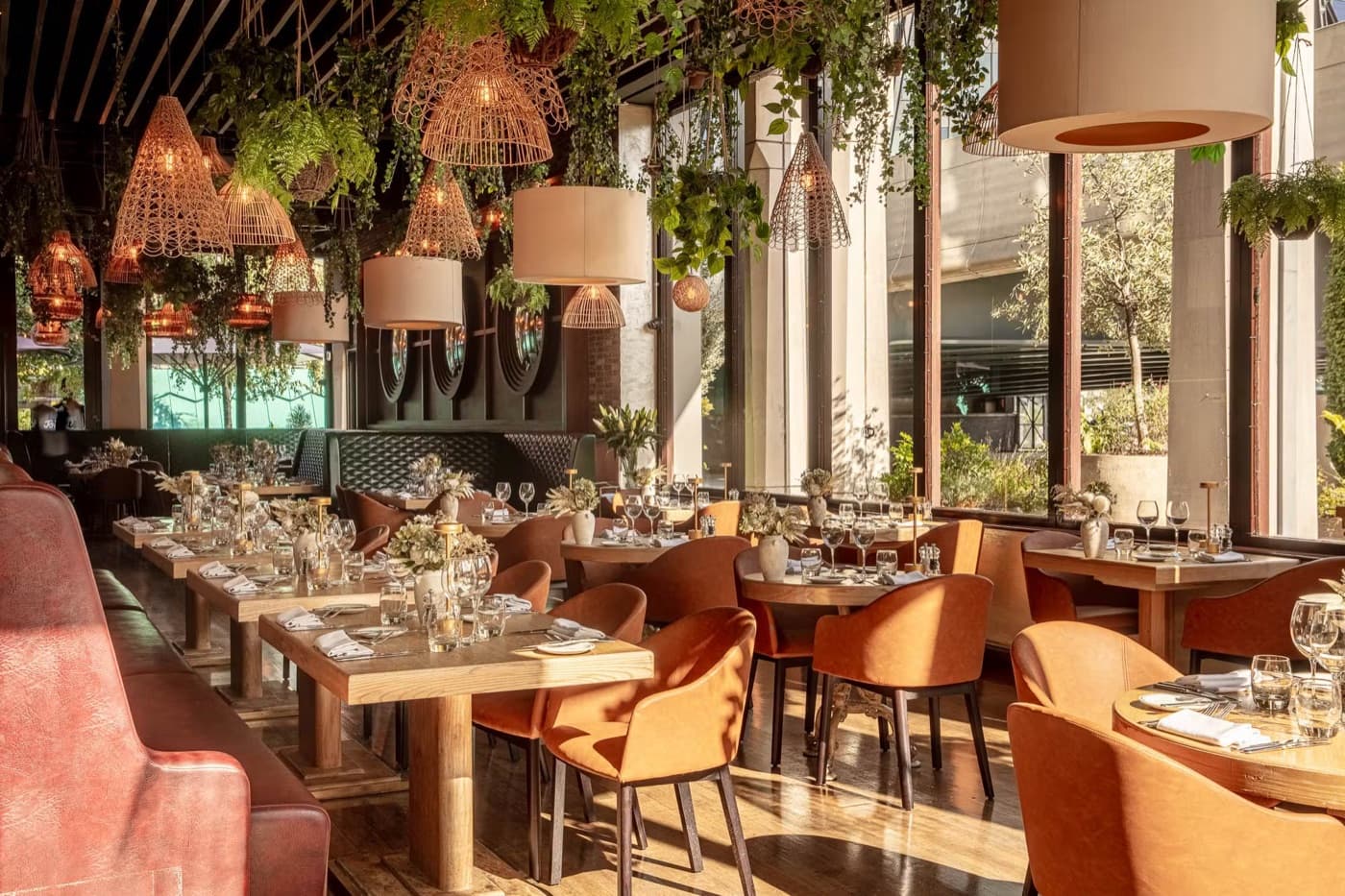 Comedor lleno de plantas y luz natural con sillas de terracota en Smith's Bar & Grill