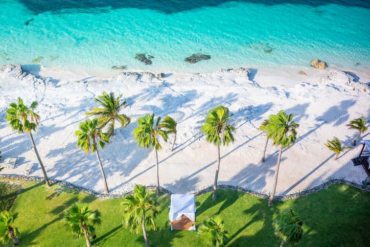 Aerial view of a Mexican beach resort with turquoise water, palm trees, and white sand